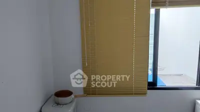 Minimalist bathroom with window and blinds, featuring a unique decor element.