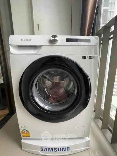 Modern Samsung washing machine in a stylish apartment setting with balcony view.