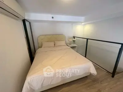 Cozy bedroom with modern decor and glass railing, perfect for urban living.