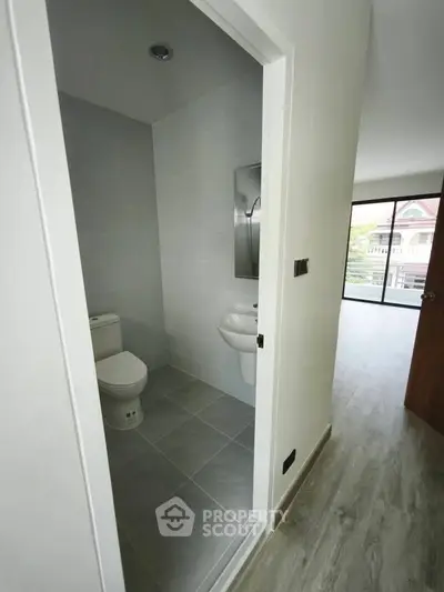 Modern apartment interior with bathroom and open living space, featuring sleek flooring and natural light.