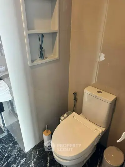 Modern bathroom with sleek toilet and built-in shelving, featuring elegant marble flooring.