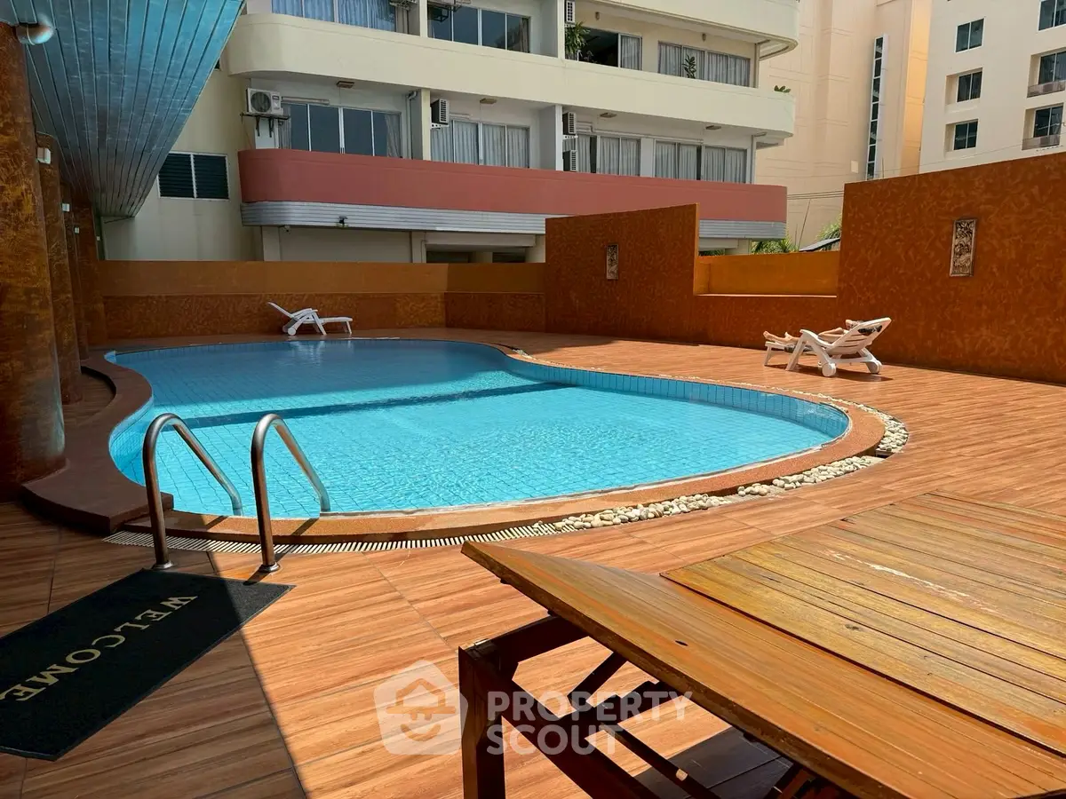 Luxurious poolside area with elegant wooden deck and modern apartment backdrop.