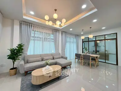Modern living room with elegant lighting and open kitchen layout, featuring a cozy gray sofa and stylish dining area.