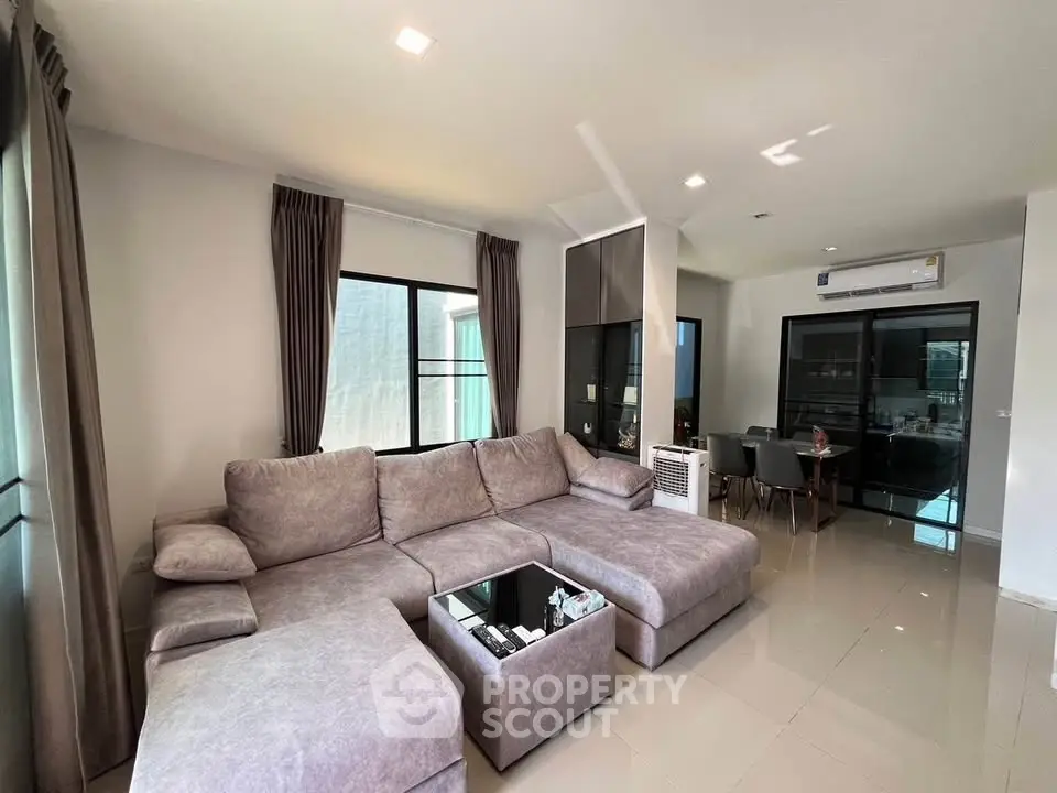 Spacious modern living room with plush sectional sofa and dining area, perfect for family gatherings.