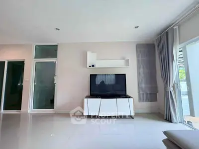 Modern living room with sleek TV setup and large windows for natural light.