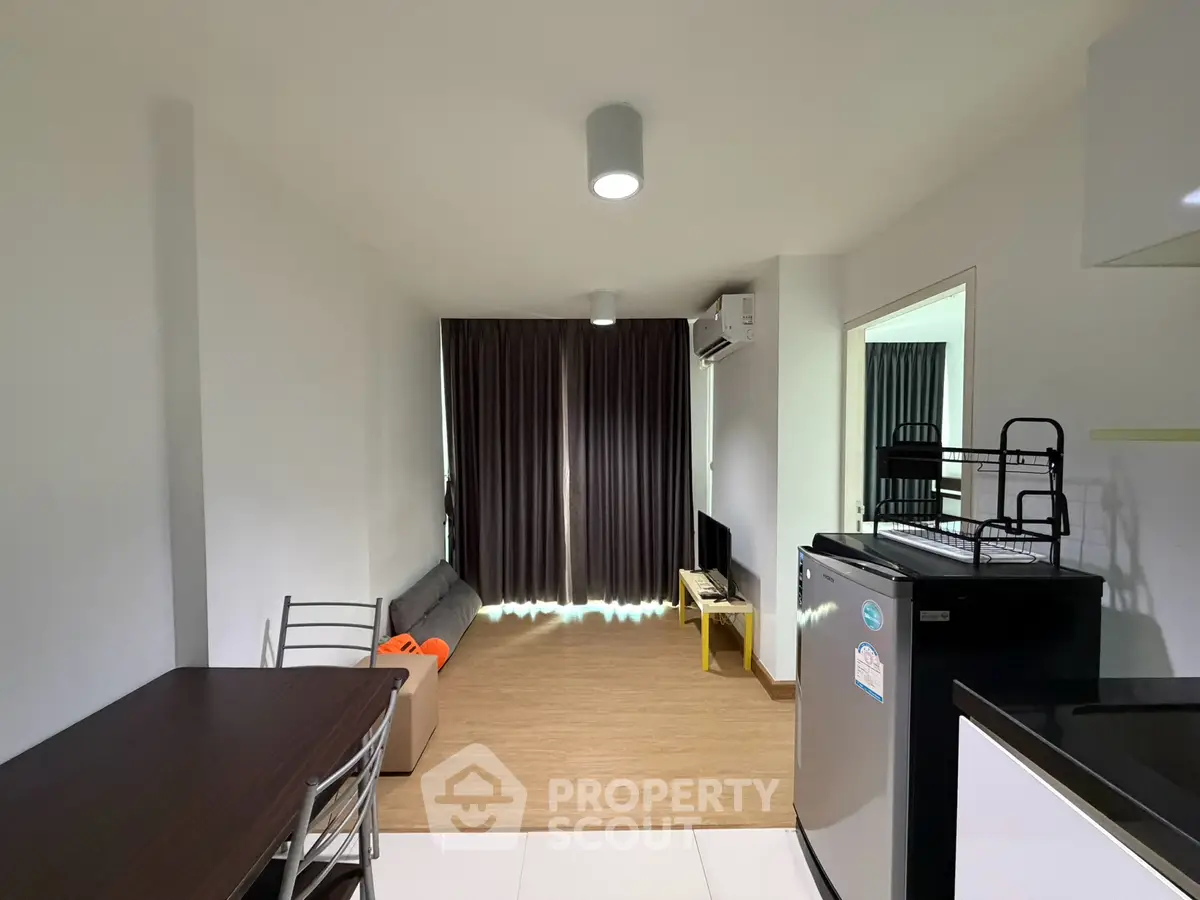 Modern living room with sleek furniture and natural light, featuring a compact kitchen and stylish decor.
