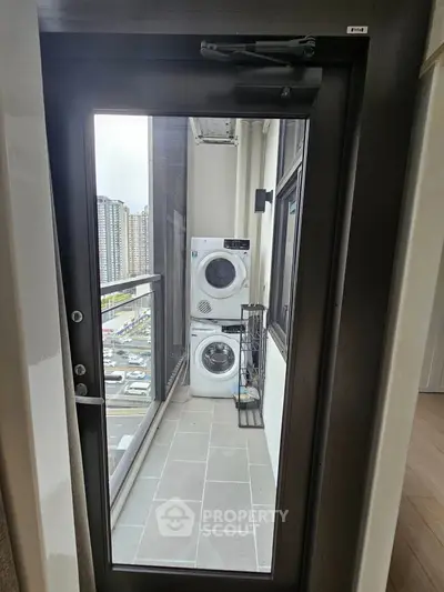 Modern balcony with washer and dryer overlooking cityscape, perfect for urban living convenience.