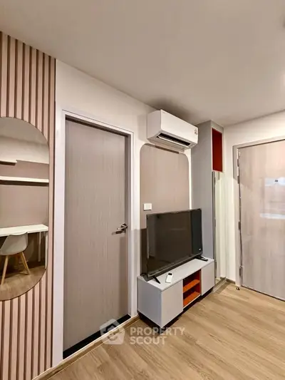 Modern living room with sleek design, featuring a TV, air conditioning, and stylish wooden accents.
