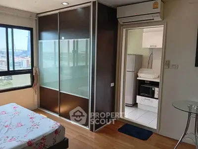 Modern bedroom with large window and view, adjacent to compact kitchen area.