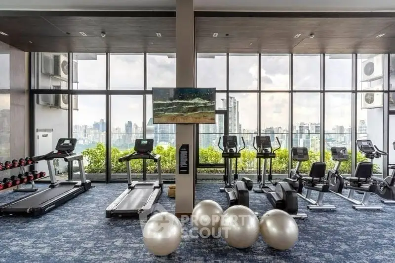 Modern gym with city view and exercise equipment in luxury high-rise building.