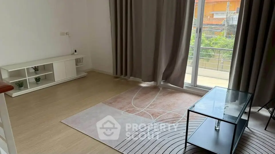 Spacious living room with modern decor and large window leading to balcony.
