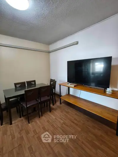 Modern dining area with wooden flooring and large TV, perfect for family gatherings.
