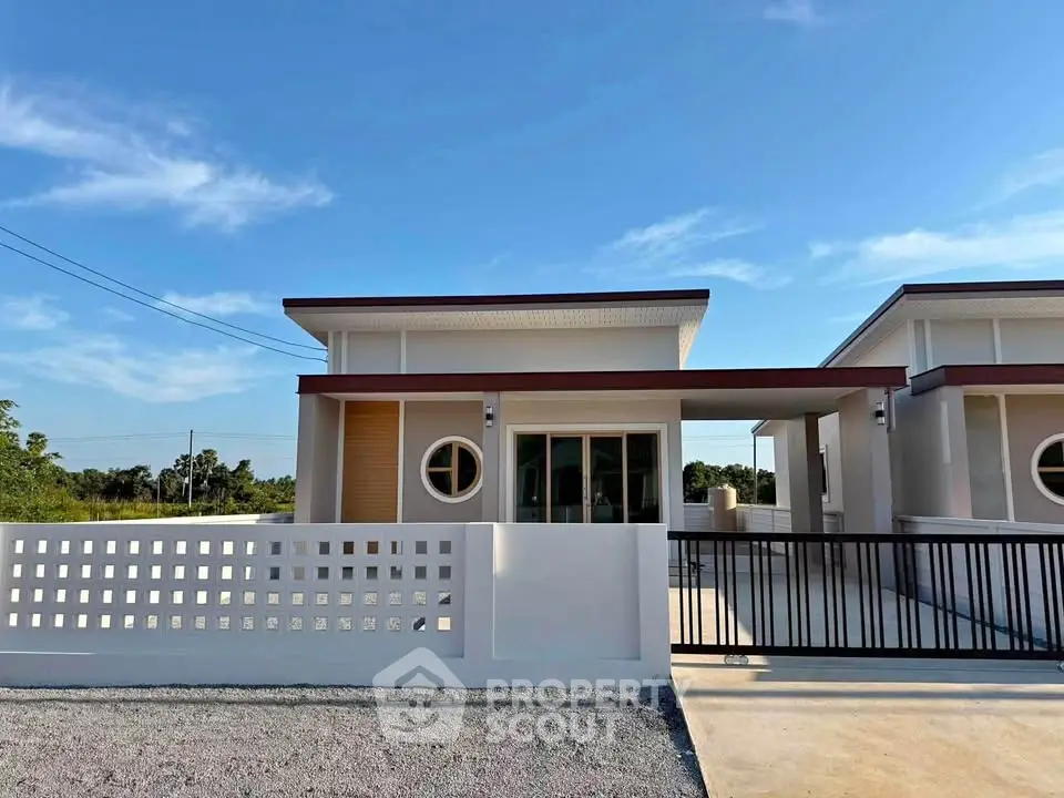 Modern single-story house with minimalist design and spacious driveway under clear blue sky.