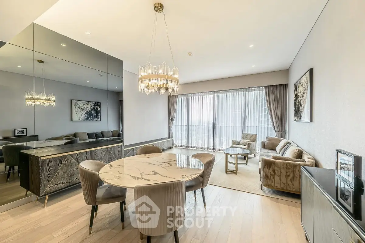 Luxurious modern living room with elegant chandelier and marble dining table, featuring floor-to-ceiling windows.