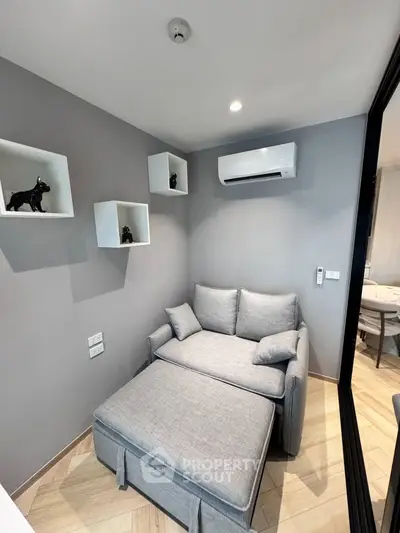 Cozy modern living room with stylish gray sofa and wall-mounted air conditioner, perfect for relaxation.