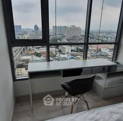 Modern high-rise apartment with stunning city view from bedroom window, featuring sleek desk and chair.