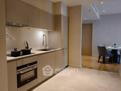 Modern kitchen with sleek cabinetry and dining area in elegant apartment