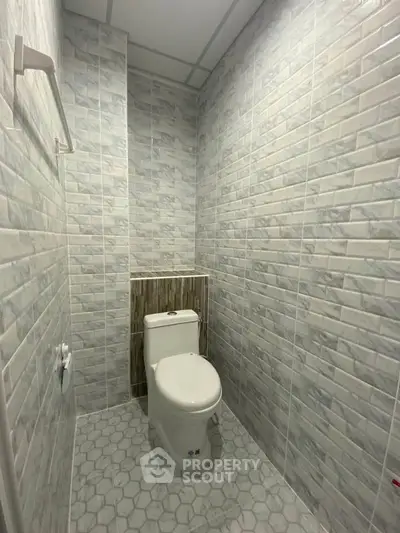 Modern bathroom with tiled walls and floor featuring a sleek toilet design.
