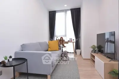 Modern living room with stylish decor and natural light, featuring a cozy sofa and entertainment unit.