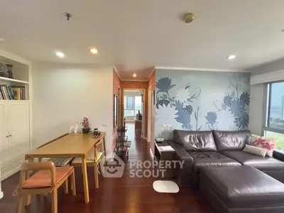 Stylish living room with modern decor and large sectional sofa, featuring floral accent wall and hardwood floors.