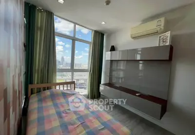 Modern bedroom with large window and city view, featuring sleek wall storage and air conditioning.