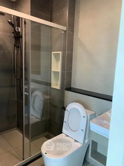 Modern bathroom with glass shower and sleek fixtures in contemporary apartment.