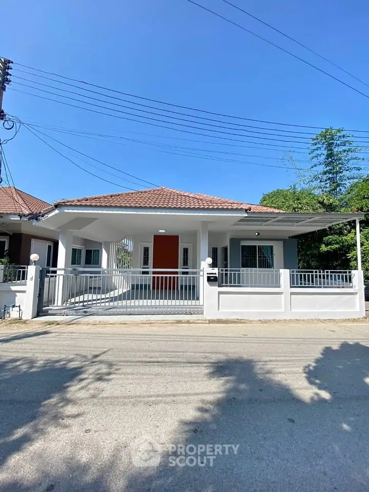 Charming single-story house with red door and spacious driveway under clear blue sky.