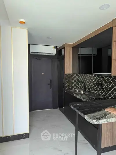 Modern kitchen with sleek black cabinetry and stylish backsplash in compact layout.