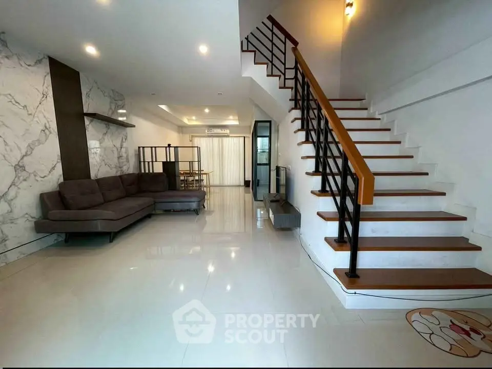 Spacious modern living room with elegant staircase and marble accent wall, perfect for stylish urban living.