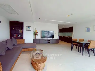 Spacious modern living room with wicker furniture and large TV, perfect for relaxation.