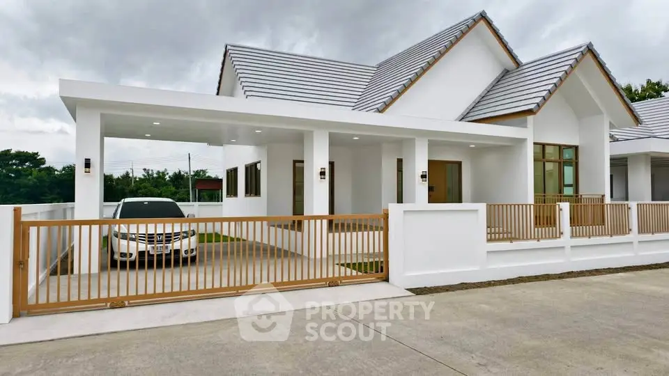 Modern white house with carport and wooden fence in suburban neighborhood