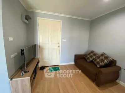 Cozy living room with modern decor and wooden flooring, featuring a comfortable sofa and flat-screen TV.