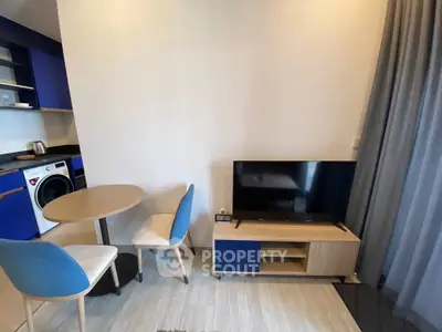 Modern living room with TV, dining set, and washing machine in compact layout.