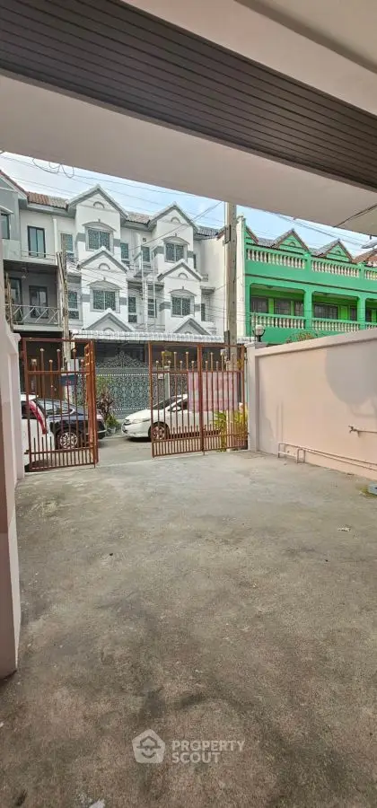 Spacious residential driveway with gated entrance and view of neighboring houses.