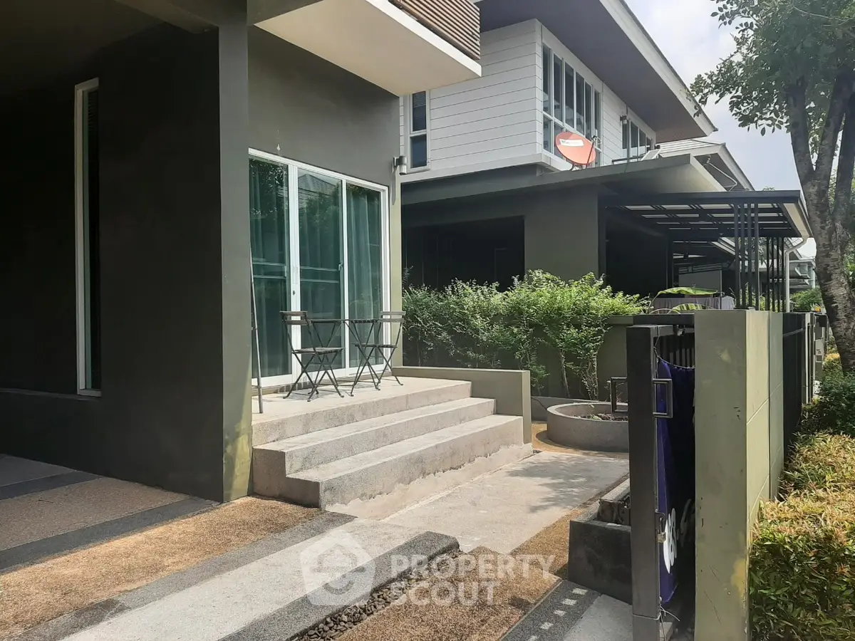 Modern residential exterior with patio and greenery, showcasing contemporary architecture and inviting outdoor space.