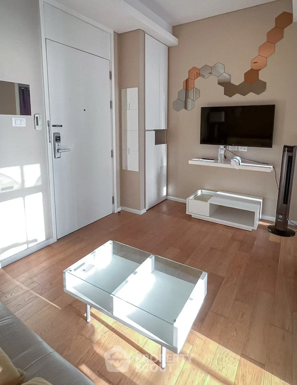 Modern living room with stylish decor and wall-mounted TV, featuring wooden flooring and contemporary furniture.