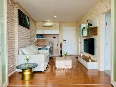 Modern living room with stylish decor and wooden flooring, featuring a cozy sofa and wall-mounted TV.