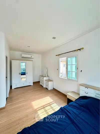Spacious bedroom with wooden flooring and natural light in modern home