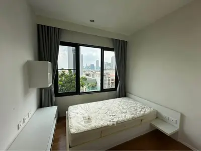 Modern bedroom with city view, featuring a large window and minimalist decor.