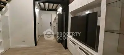 Modern living room with sleek TV setup and stylish hallway leading to kitchen.