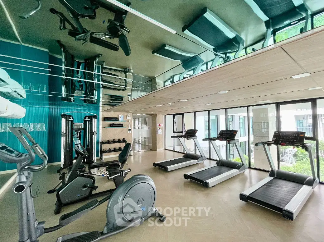 Modern gym with state-of-the-art equipment and mirrored ceiling in luxury residential building.
