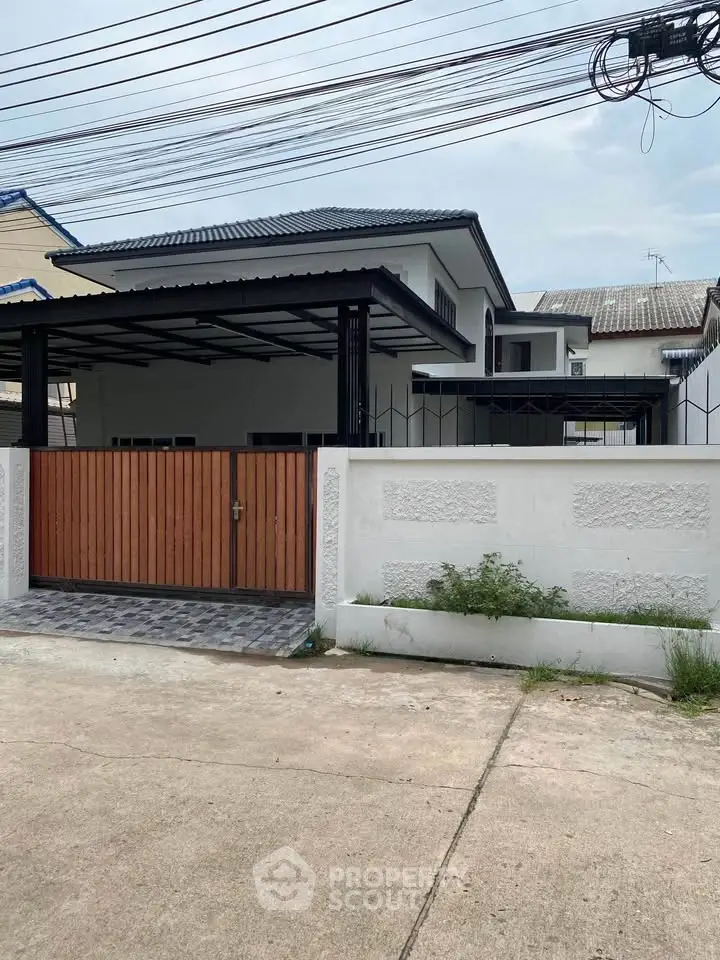 Charming suburban house with gated driveway and modern roof design.