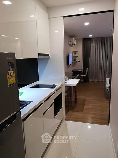 Modern open-layout kitchen with sleek appliances and view into cozy living area.