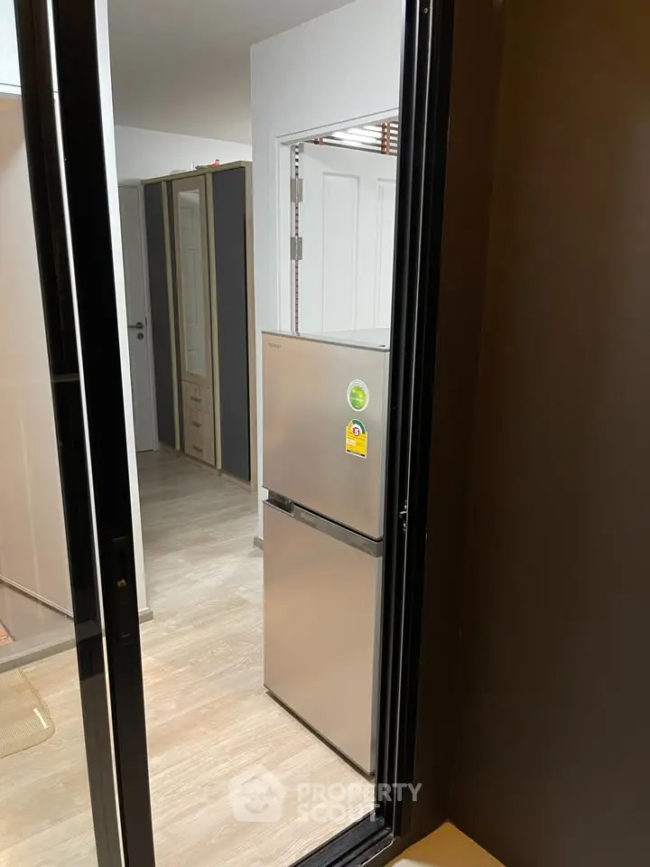 Modern apartment interior with sleek fridge and wooden flooring