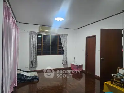 Spacious living room with wooden flooring and air conditioning, ideal for cozy family gatherings.