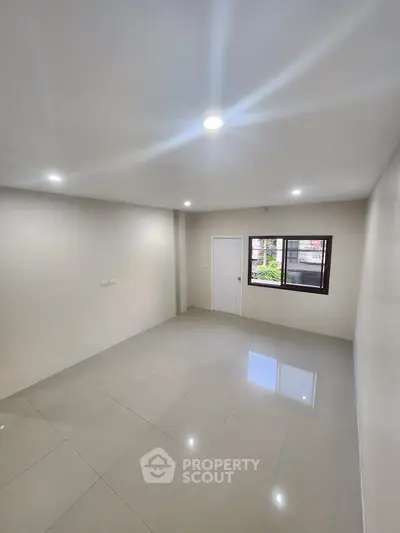 Spacious unfurnished room with large window and bright lighting, perfect for customization.