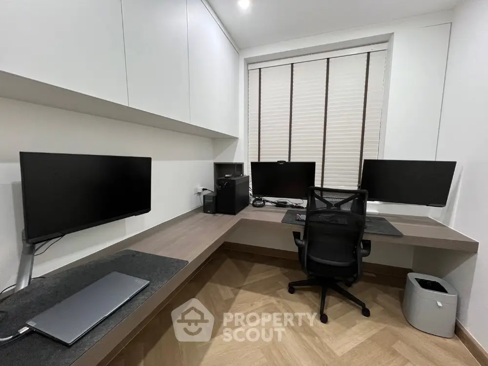 Modern home office with sleek desk, multiple monitors, and ergonomic chair