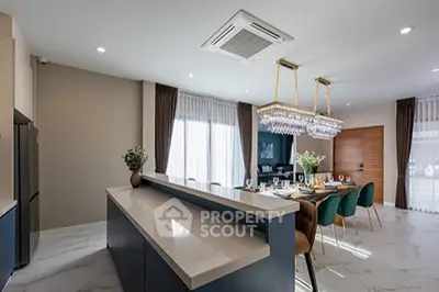 Luxurious open-layout kitchen and dining area with elegant chandelier and modern design.