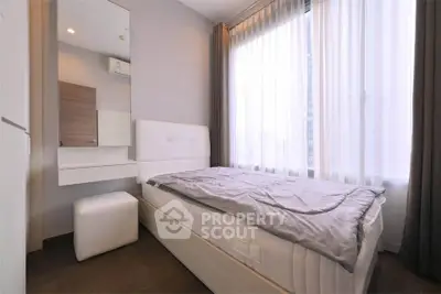 Modern bedroom with large window and stylish decor in a cozy apartment.