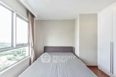 Bright bedroom with large window and minimalist decor in modern apartment.